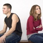Couple sitting on a bench with their backs to each other.